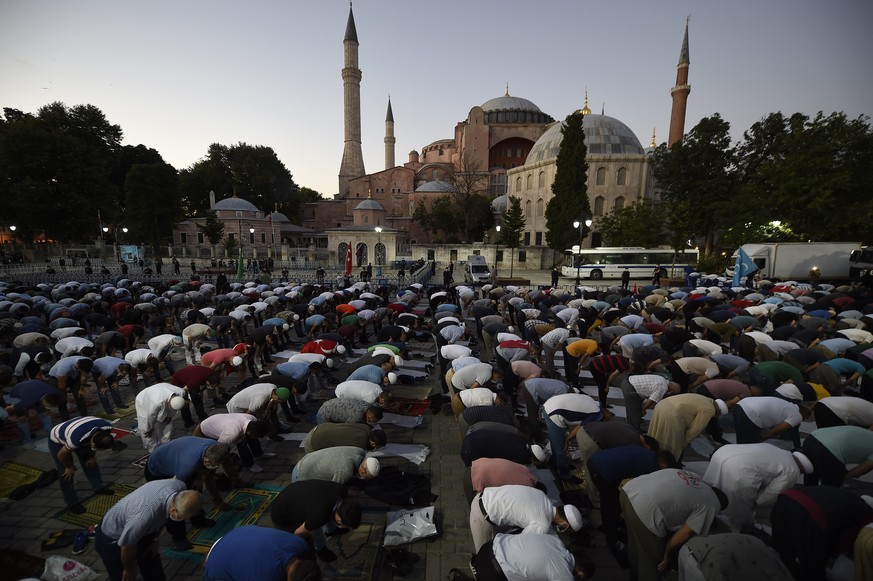Muslims offer their evening prayers outside the Byzantine-era Hagia Sophia, one of Istanbul's main tourist attractions in the historic Sultanahmet district of Istanbul, following Turkey's Council of S ...