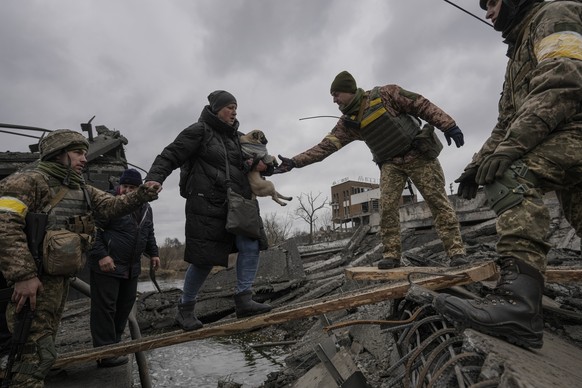 Ukrainische Soldaten helfen einer Frau dabei, den Fluss Irpin zu überqueren. 