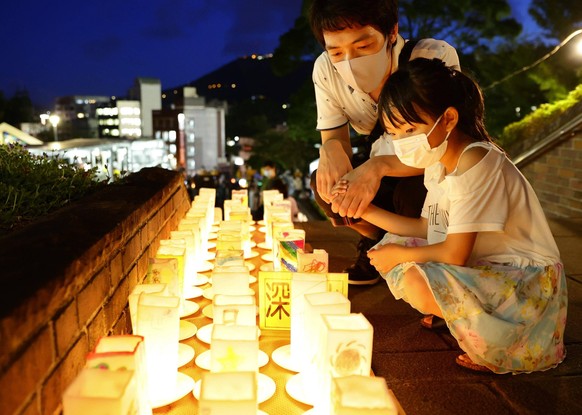 Im Friedenspark in Nagasaki zünden Menschen Kerzen für die Opfer an.