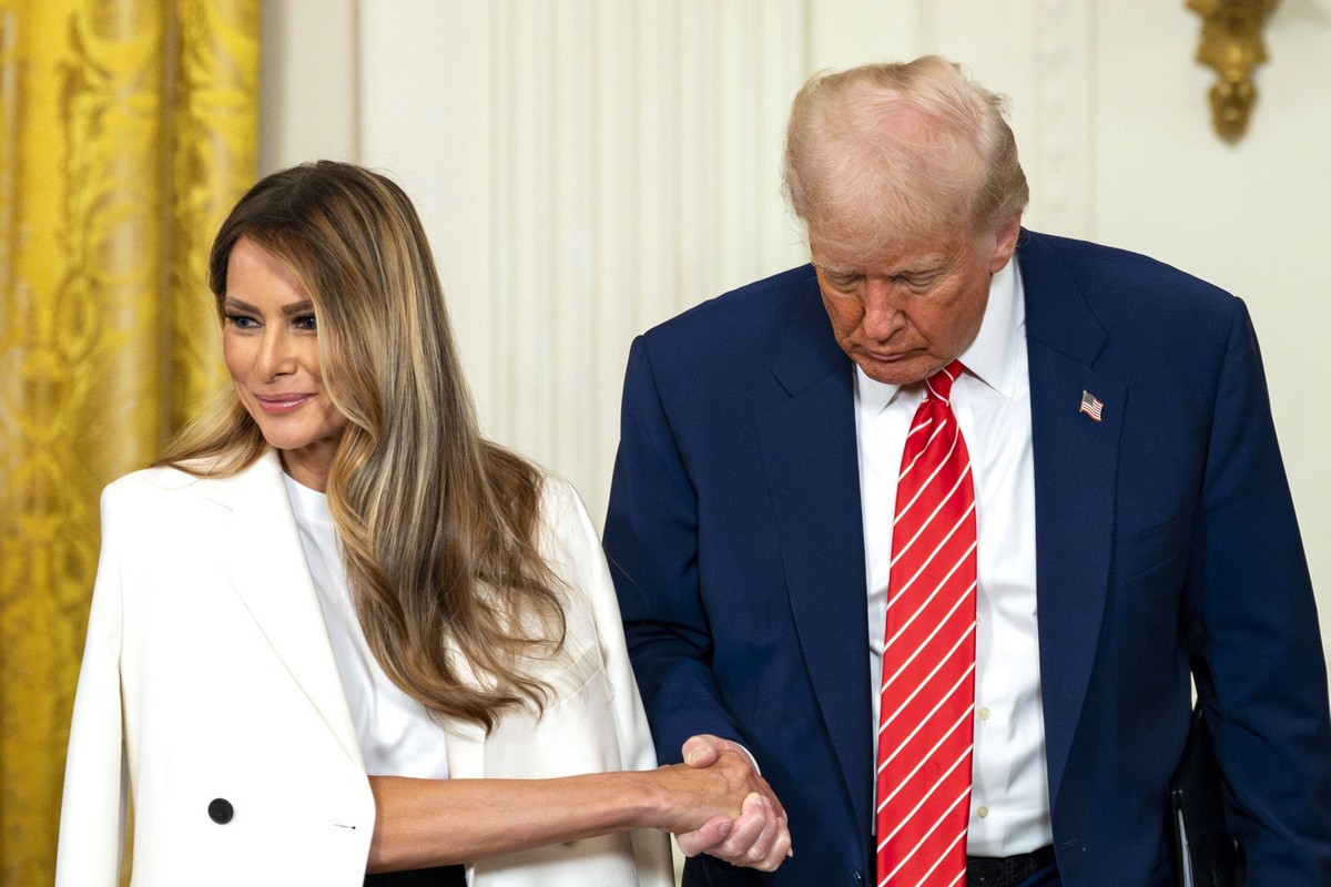 President Donald Trump grabs the hand of First Lady Melania Trump during an event celebrating military mothers in the East Room of the White House in Washington, DC on Thursday, May 8, 2025. PUBLICATI ...