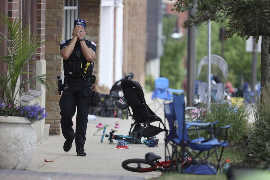 CORRECTS TO A LAKE FOREST POLICE OFFICER, INSTEAD OF LAKE COUNTY A Lake Forest, Ill., police officer walks down Central Ave in Highland Park, Ill., on Monday, July 4, 2022, after a shooter fired on th ...