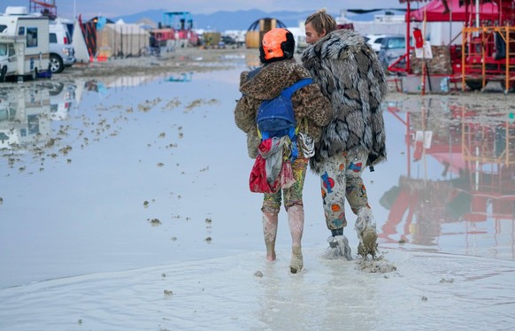 Syndication: Reno Gazette Journal Dub Kitty and Ben Joos, of Idaho and Nevada, respectively, walk through the mud at Burning Man after a night of dancing with friends. Like many attendees, the two ado ...