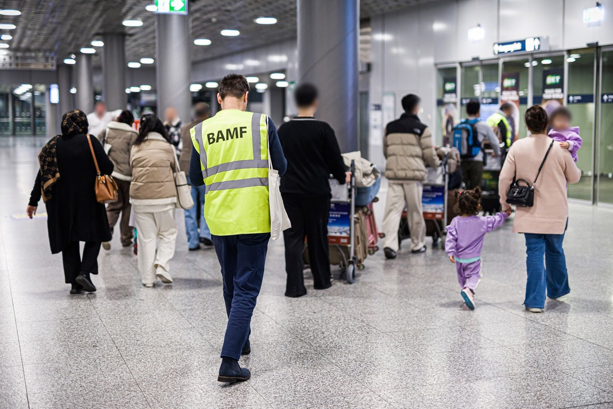 11.11.2025, Niedersachsen, Langenhagen: Menschen aus Afghanistan, die zuvor mit einem Flugzeug auf dem Flughafen Hannover-Langenhagen gelandet sind, werden von einem Mitarbeiter des Bundesamtes für Mi ...