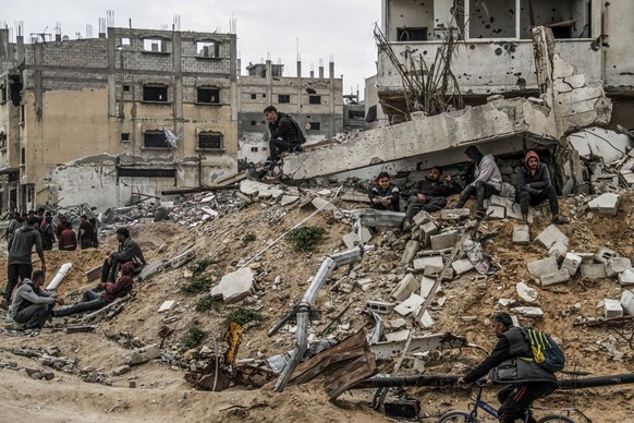ARCHIV - 25.03.2024, Palästinensische Gebiete, Jabalia: Menschen sitzen auf den Ruinen von Gebäuden, die durch israelische Luftangriffe zerstört wurden. (zu dpa: «Israel: Hamas-Kommandeur im Gazastrei ...