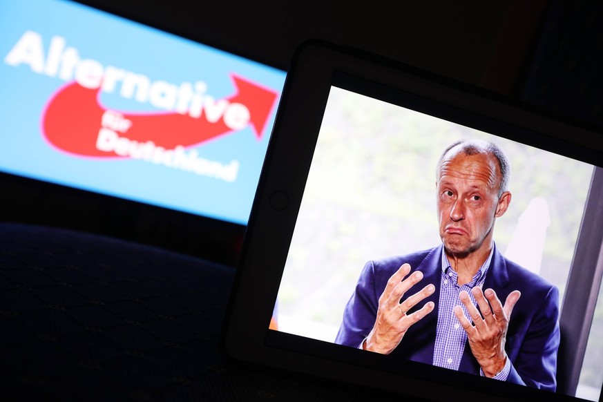 Ein AFD Logo auf einem PC-Monitor im Hintergrund und davor ein Foto von Friedrich Merz CDU auf einem iPad. Friedrich Merz steht nach seinem Aussagen im ZDF Sommerinterview bezueglich bez