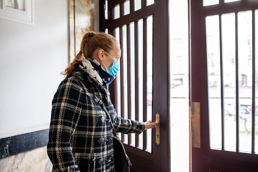 Woman wearing face mask going out during corona virus outbreak. Female going out with a protective face mask.