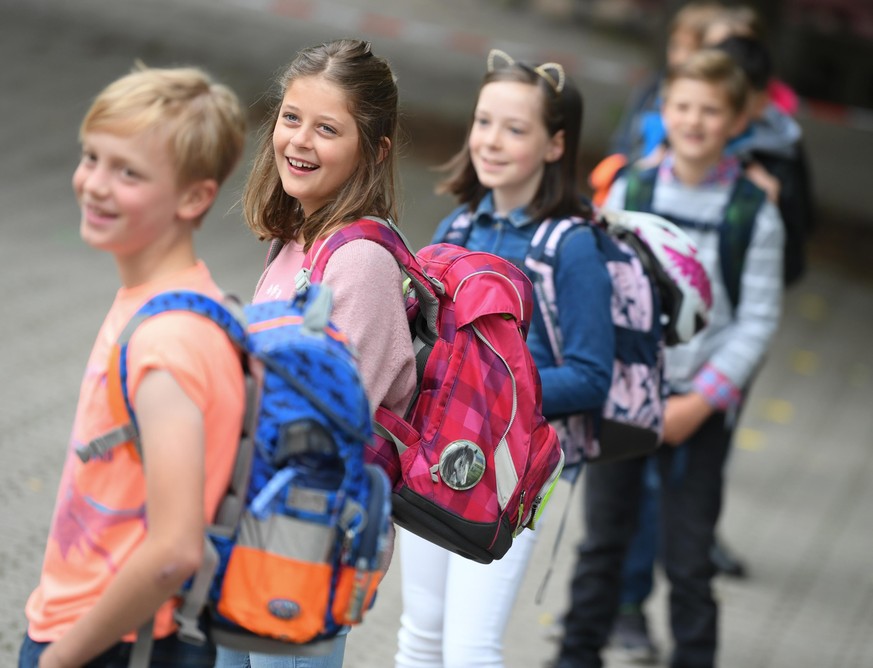 10.06.2020, Hessen, Wiesbaden: Schülerinnen und Schüler der vierten Klasse der Robert-Schumann-Grundschule stehen vor dem Unterricht auf dem Schulhof. Hessen Grundschulen beginnen am 22. Juni wieder m ...