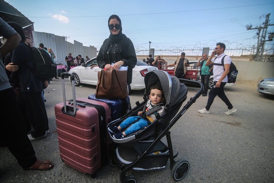 14.10.2023, Palästinensische Gebiete, Rafah: Eine palästinensische Frau und ihr Kind warten am Grenzübergang Rafah zwischen dem Gazastreifen und Ägypten. Nach den Terrorattacken der islamistischen Ham ...