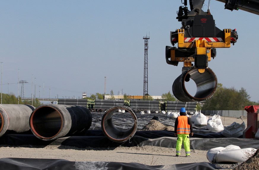 FILE PHOTO: A worker watches as pipes are piled up at a storage area at French pipe coating company EUPEC in Sassnitz May 6, 2011. EUPEC is working to complete around 200,000 pipes for Nord Stream. RE ...