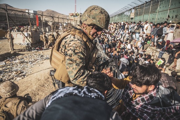 STYLELOCATIONA U.S. Marine with the Special Purpose Marine Air-Ground Task Force Crisis Response team, assist Afghan refugees at the Evacuation Control Center at Hamid Karzai International Airport dur ...
