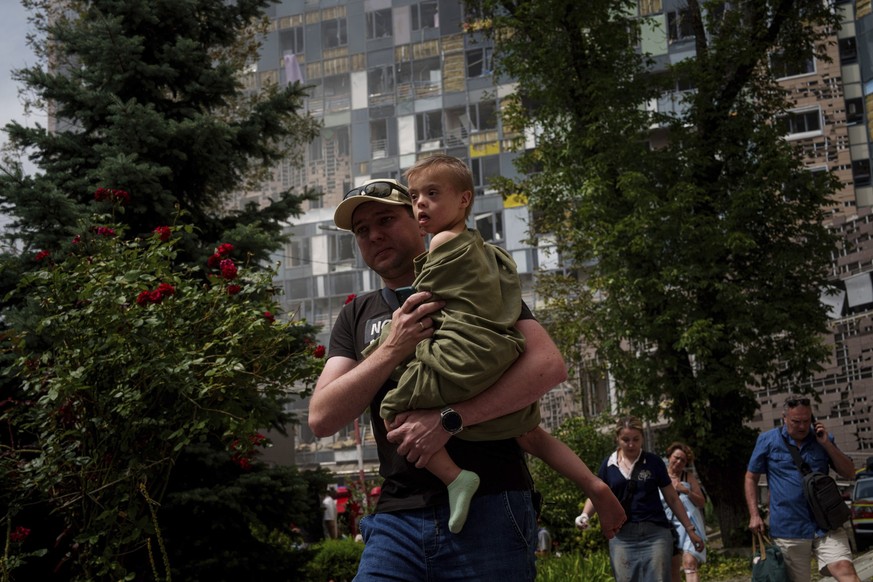 08.07.2024, Ukraine, Kiew: Ein Kind wird in der Nähe des von russischen Raketen getroffenen Okhmatdyt-Kinderkrankenhauses getragen. Russische Raketen haben mehrere Menschen getötet und ein Kinderkrank ...