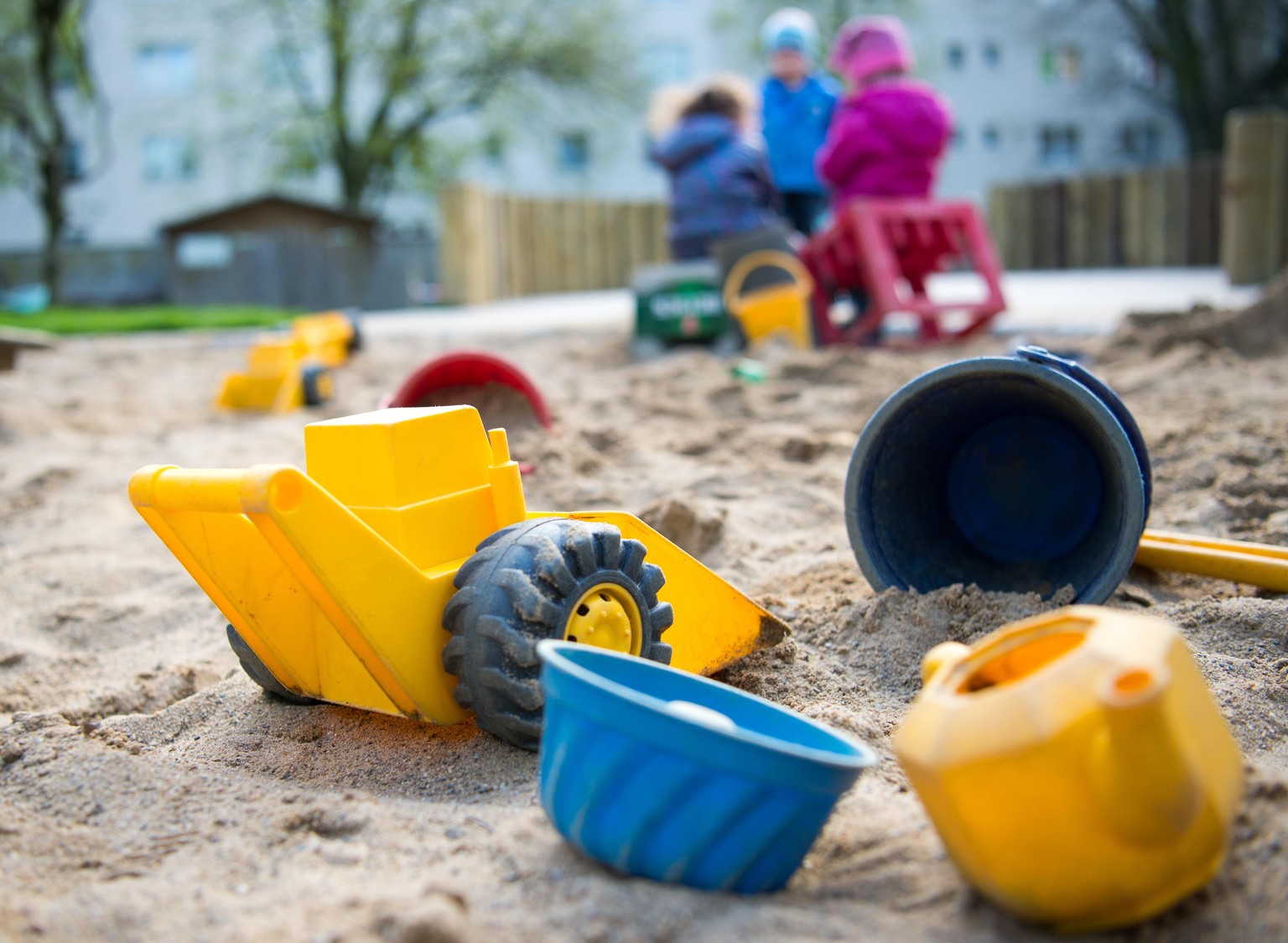 ARCHIV - 18.04.2016, Nordrhein-Westfalen, Düsseldorf: Spielzeug liegt in einem Sandkasten während Kinder spielen in einer Kindertagesstätte. (zu dpa: &quot;Mit Schnupfen in die Kita? Eltern und Erzieh ...