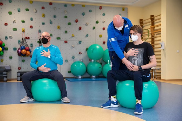 Die long-covid-Patienten Jörg Schneider (l) und Ulrich Lowers (r) machen ein Atemtraining mit Physiotherapeut Mirko Weernink (M) in einem Gymnastikraum der Klinik Teutoburger Wald, eine Reha-Klinik fü ...