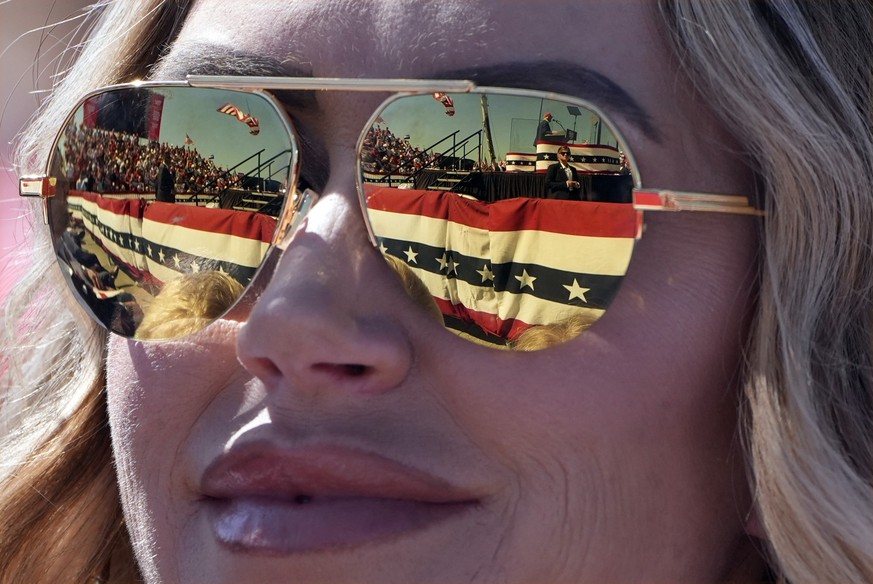 Republican presidential nominee former President Donald Trump is reflected in the sunglasses of Lara Trump at a campaign rally at Wilmington International Airport, Saturday, Sept. 21, 2024, in Wilming ...