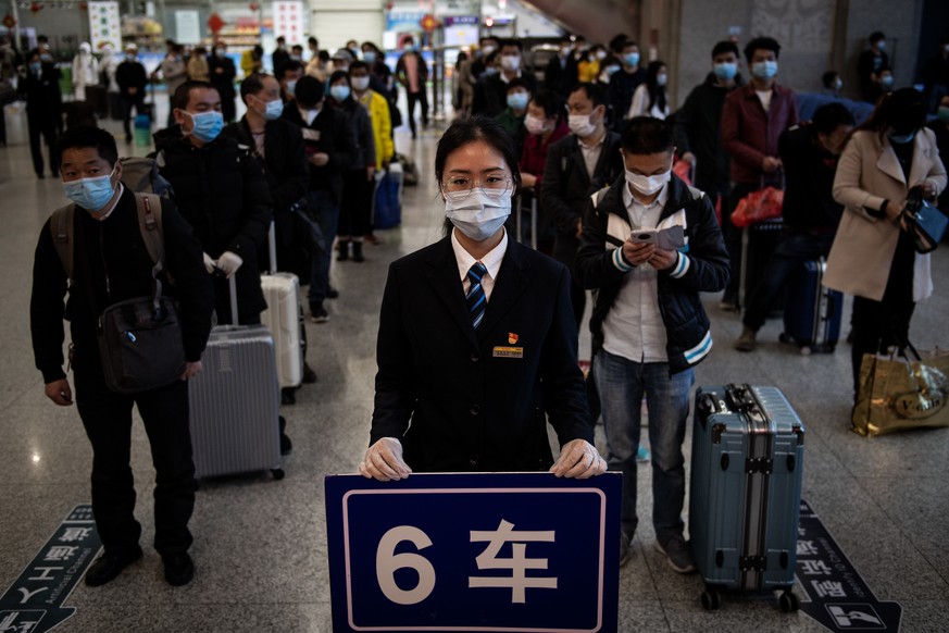 08.04.2020, Wuhan: Passengers wear face masks standing in line to take temperature check. 
At 00:50 on 8th, April, 2020, Trains K81 departs from Wuchang railway station in Wuhan, middle China's Hubei  ...