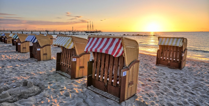 Abendliche Stimmung beim Sonnenuntergang am Strand mit Blick auf das Meer und mehrere Starndkörbe

Steuer Steuer Bild übersteuert