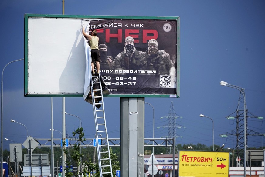 FILE - A man takes down the poster with writing reading &quot;Join us at Wagner&quot;, which is associated with the owner of the Wagner private military contractor, Yevgeny Prigozhin, is seen above a  ...