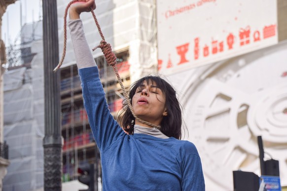 December 17, 2022, London, England, United Kingdom: A protester performs a dance with a noose around her neck. A group of women staged a demonstration and performance in Piccadilly Circus in protest a ...