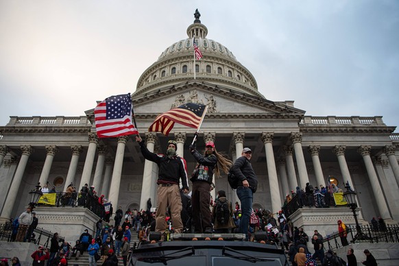 210106 Pro-Trump supporters wave with flags outside the United States Capitol Building after it being stormed during a March to Save America Rally on January 6, 2021 in Washington, DC, USA. Photo: Joe ...