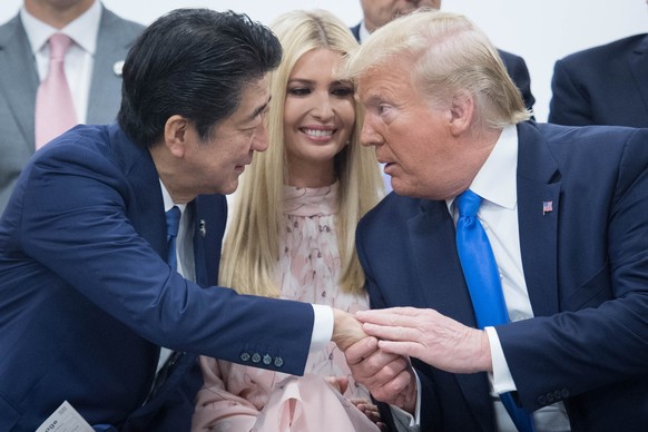 ARCHIV - 29.06.2019, Japan, Osaka: Der damalige japanische Premierminister Shinzo Abe (l) sch�ttelt dem damaligen US-Pr�sidenten Donald Trump die Hand, w�hrend die Beraterin des US-Pr�sidenten, seine  ...