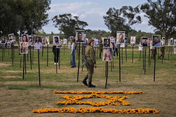 Israeli soldiers and others look at photos of people killed and taken captive by Hamas militants during their violent rampage through the Nova music festival in southern Israel, which are displayed at ...