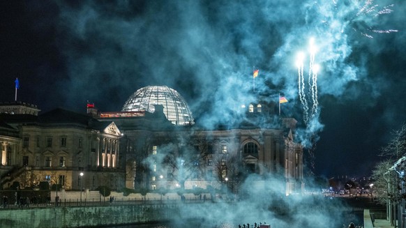 31.12.2022, Berlin: An der Spree vor dem Reichstagsgebäude wird Feuerwerk abgebrannt. Foto: Christophe Gateau/dpa +++ dpa-Bildfunk +++