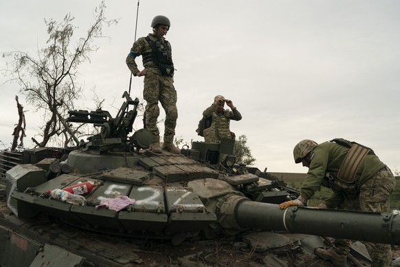 Ukrainische Soldaten auf einem zerstörten russischen Panzer in der Region Charkiw.