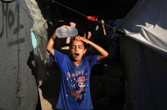 Heat Wave In Deir al-Balah A displaced Palestinian girl is splashing her face with water in front of her tent during a heatwave in Deir al-Balah, in the central Gaza Strip, on June 11, 2024, amid the  ...