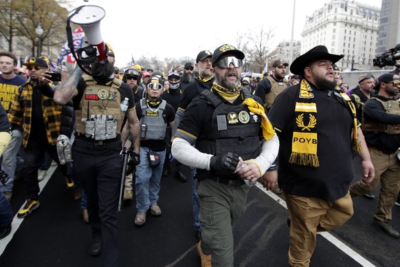 FILE - Supporters of President Donald Trump who are wearing attire associated with the Proud Boys attend a rally at Freedom Plaza, Dec. 12, 2020, in Washington. The supporter on the left is wearing a  ...