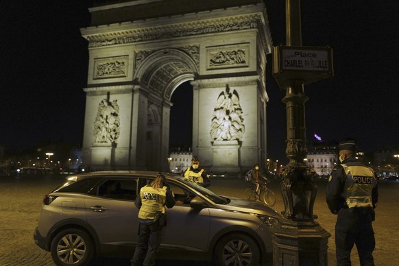 French police officers control a car next to the Arc de Triomphe, near the Champs Elysees, as they enforce a curfew, in Paris, France, Tuesday Dec. 15, 2020. France on Tuesday is lifting a lockdown im ...