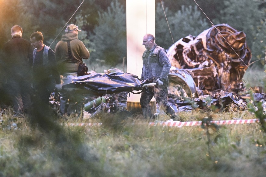 24.08.2023, Russland, Kushenkino: Menschen tragen einen Leichensack aus dem Wrack eines abgestürzten Privatjets in der Nähe des Dorfes Kuschenkino in der Region Twer. Der russische Söldnerführer Jewge ...