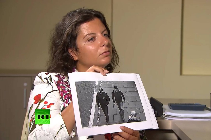 Eine russische Journalistin hält ein Foto der zwei mutmaßlichen Täter im Fall Skripal in die Kamera.