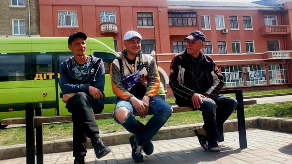 Drei Männer warten an einer Geflüchtetenunterkunft in Kramatorsk.