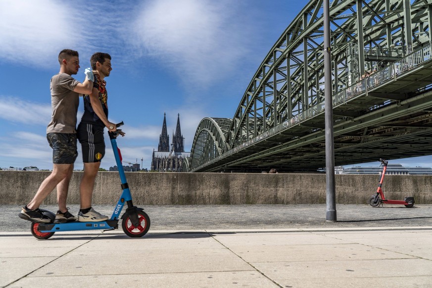 Elektrorolle, E-Scooter, zwei Personen auf einem Mietroller, am Rheinufer, Köln-Deutz, Rheinboulevard, Hohenzollernbrücke, Kölner Dom, Köln, NRW, Deutschland, Elektroscooter *** electric scooter, two  ...