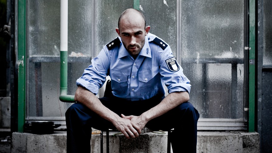 police officer with bald head sits in an old abandoned greenhouse