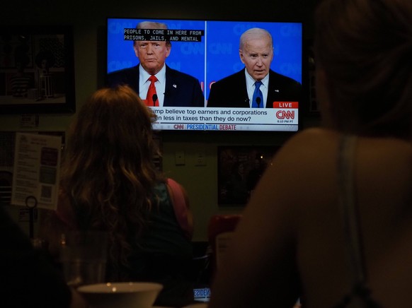 June 27, 2024, Takoma Park, Maryland, USA: People watch the President Joe Biden and former President Donald Trump debate on a TV screen at a local restaurant. Takoma Park USA - ZUMAd155 20240627_znp_d ...