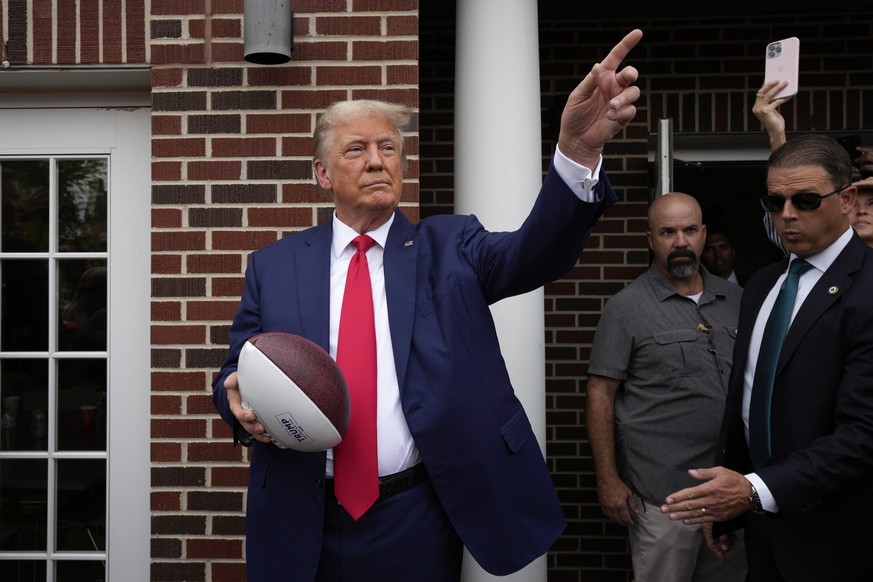 Former President Donald Trump holds a football before throwing it to the crowd during a visit to the Alpha Gamma Rho, agricultural fraternity, at Iowa State University before an NCAA college football  ...