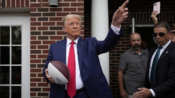 Former President Donald Trump holds a football before throwing it to the crowd during a visit to the Alpha Gamma Rho, agricultural fraternity, at Iowa State University before an NCAA college football  ...