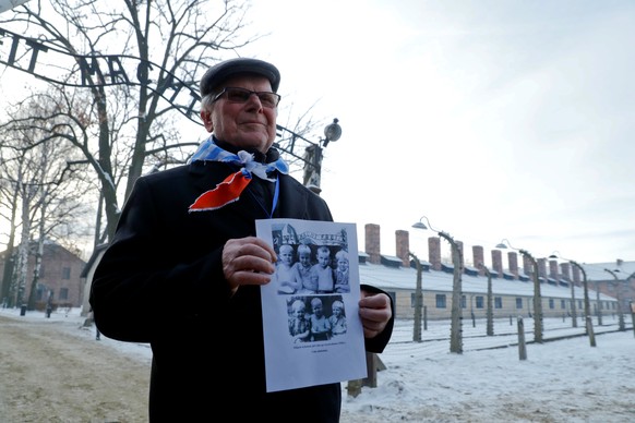 REFILE - CLARIFYING LOCATION A survivor holds a poster at the former Nazi German concentration and extermination camp Auschwitz, as he attends ceremonies marking the 74th anniversary of the liberation ...