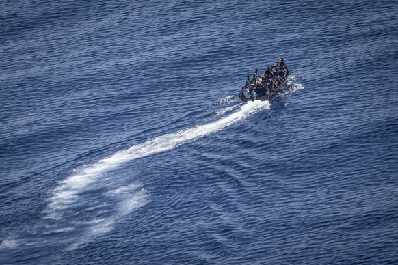 PRODUKTION - 29.06.2023, Italien, Lampedusa: Migranten steuern ein Boot von der Nordk�ste Afrikas �ber das Mittelmeer in Richtung der italienischen Insel Lampedusa. Von Tunesien aus setzen immer mehr  ...