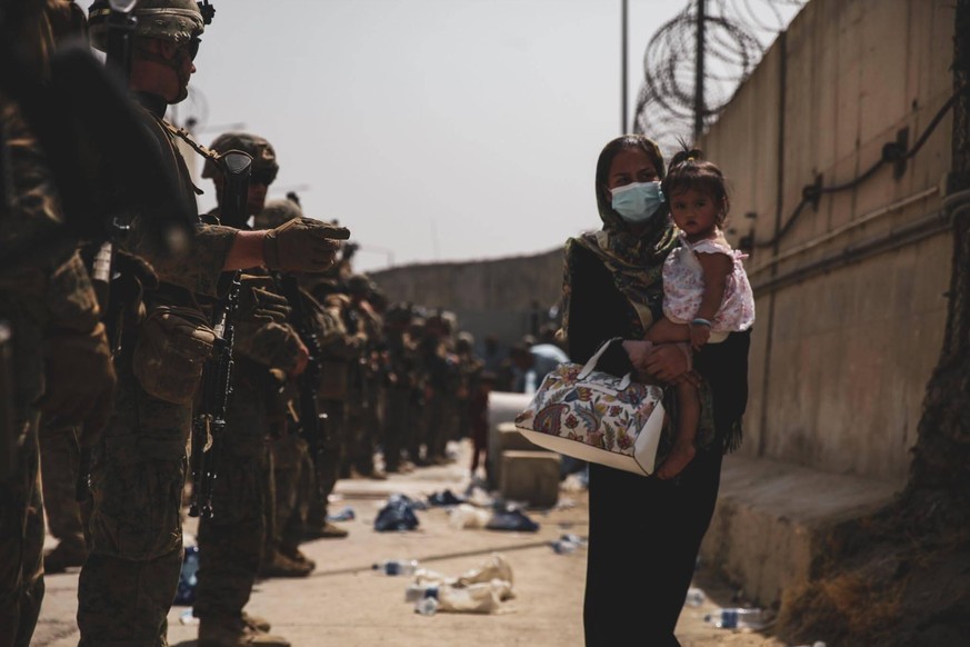 Soldaten schützen eine Evakuierte mit Baby