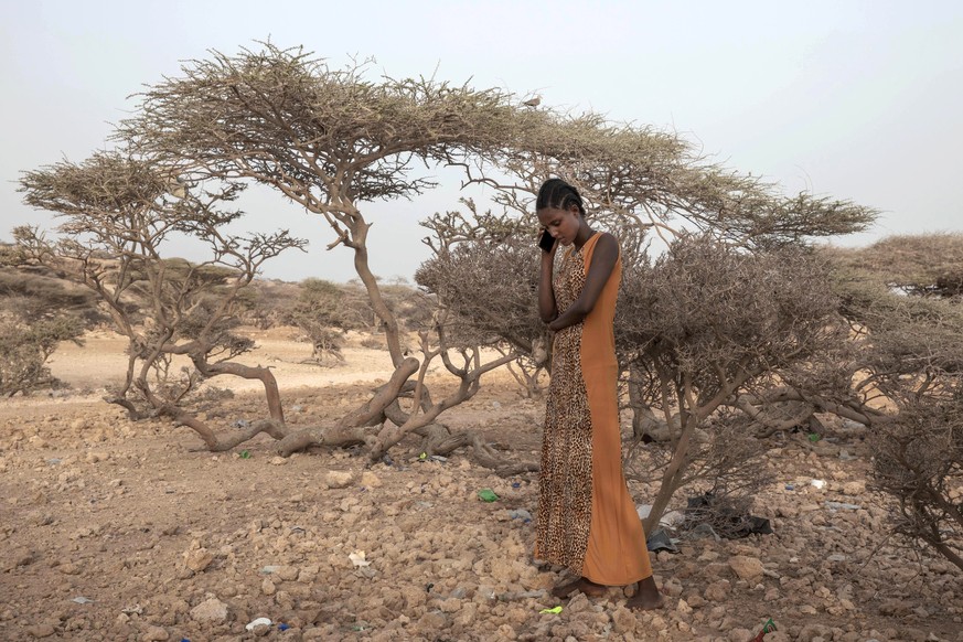 FILE - In this July 15, 2019 file photo, an Ethiopian Tigray migrant, makes a phone call to her mother in Ethiopia, as she takes shelter under trees at the last stop of her journey before leaving by b ...