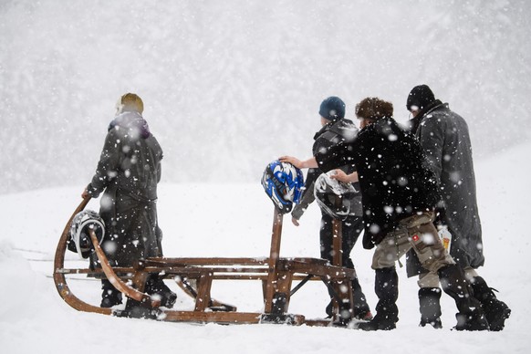 06.01.2019, Bayern, Garmisch-Partenkirchen: Teilnehmer des traditionellen Hornschlittenrennens schieben ihren Schlitten zum Startbereich den Berg hinauf. Foto: Matthias Balk/dpa +++ dpa-Bildfunk +++