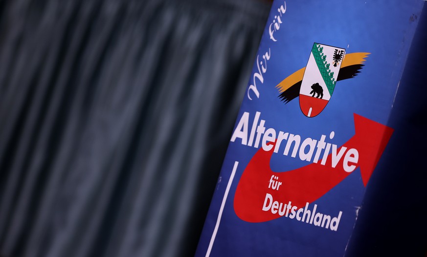 ARCHIV - 20.12.2020, Sachsen-Anhalt, Magdeburg: Ein Logo der AfD Sachsen-Anhalt ist auf einem Rednerpult in der Messehalle zu sehen. (zu dpa