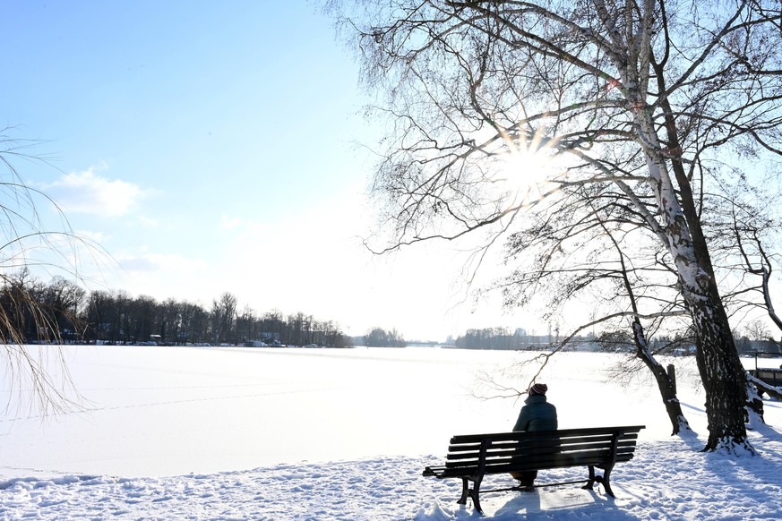 Pause auf einer Bank beim Winterspaziergang an dem zugefrorenen Tegeler See in Tegelort, Reinickendorf, Berlin, Deutschland *** Break on a bench during a winter walk at the frozen Tegeler See in Tegel ...