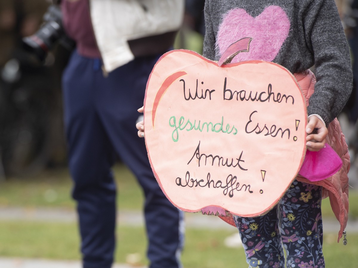 15.10.2022, Berlin: Ein Kind hält bei der Kundgebung der Initiative #ichbinarmutsbetroffen am Bundeskanzleramt ein Plakat mit der Aufschrift «Wir brauchen gesundes Essen! Armut abschaffen!». #IchBinAr ...