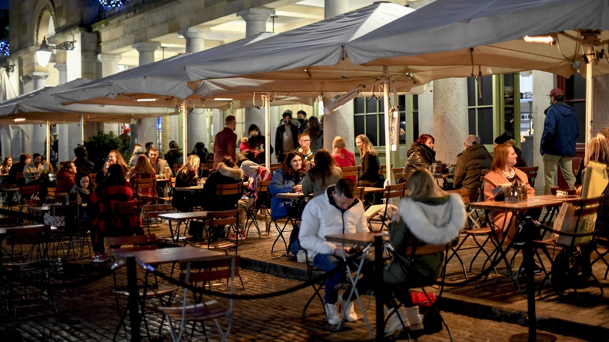 People sit at tables in Covent Garden, in London, Saturday, Dec. 12, 2020. Health Secretary Matt Hancock says infections are starting to rise in some areas after falling during a four-week national lo ...