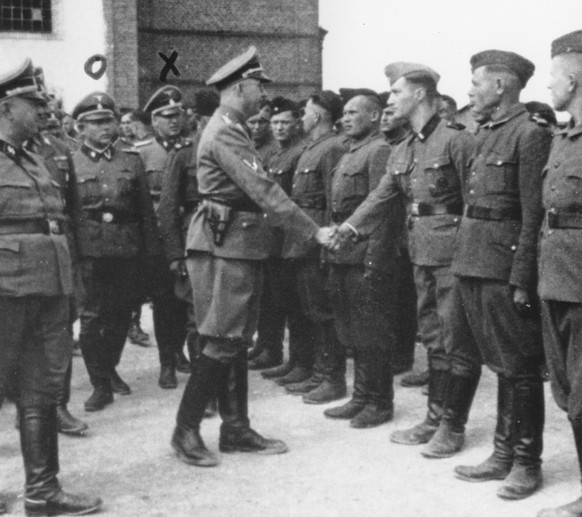 This 1942 photo provided by the the public prosecutor's office in Hamburg via the United States Holocaust Memorial Museum, shows Heinrich Himmler, center left, shaking hands with new guard recruits at ...