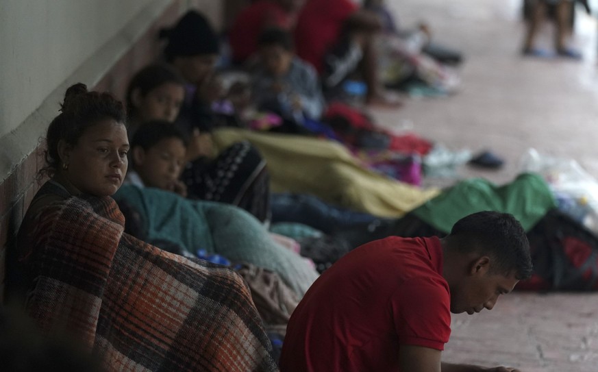 13.05.2023, Mexiko, Matamoros: Migranten aus Venezuela sitzen an einer Hauswand und suchen Schutz vor dem Regen in der Nähe des Ufers des Rio Grande. Mit dem Ende des Corona-Notstands in den USA lief  ...