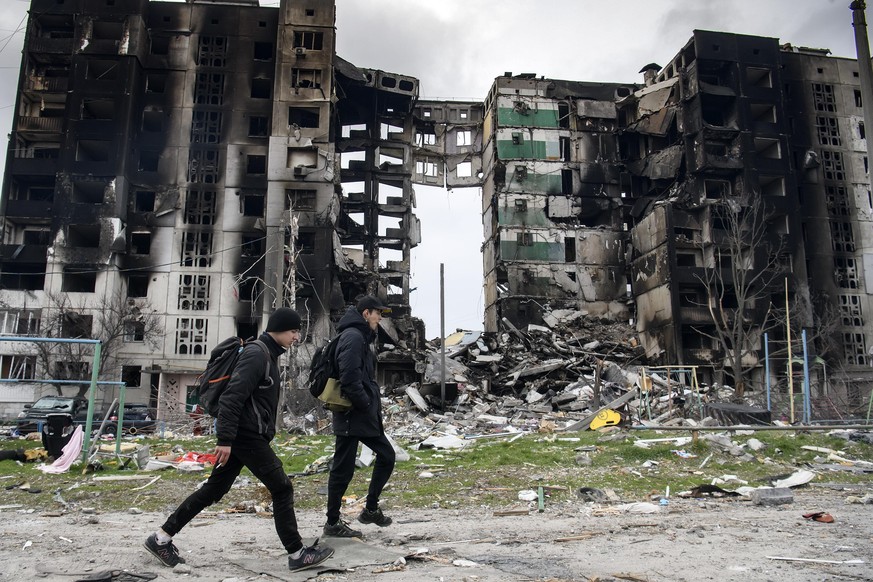 Ukrainians walk next to destroyed buildings in Borodianka, located northwest of Kyiv, on Tuesday, April 5, 2022. The European Union is considering a new round of sanctions against Russia after condemn ...